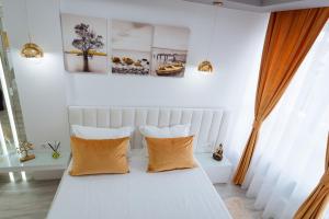 a bedroom with a white bed with orange pillows at GoldenLux Apartments in Oradea