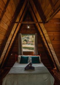 Cama en habitación de madera con ventana en Recanto do Vale en Pomerode