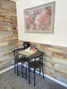 Gatwick Deluxe En-suite Rooms في هورلي: طاولة وكرسي في غرفة بجدار خشبي
