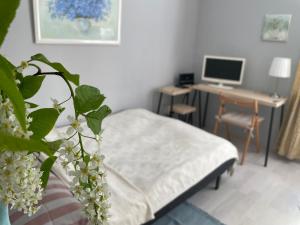Schlafzimmer mit einem Bett und einem Schreibtisch mit einem Computer in der Unterkunft Linden Blossom in Liepāja