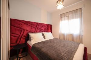 a bedroom with a bed with a red headboard at Boutique Apartments Ad Astra in Bibinje