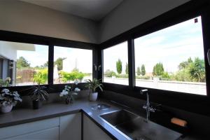 una cocina con fregadero y ventanas con plantas en Casa moderna a 300 metros de la playa. en San Jose de sa Talaia