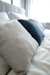 almohada azul sobre una cama blanca en Tatyana-Hotel en Kostanái