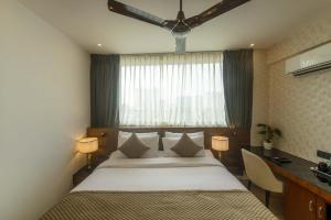 a bedroom with a bed and a desk and a window at Royal Ace Boutique Hotel - Manyata Techpark in Bangalore