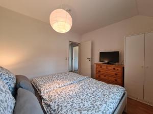 a bedroom with a bed and a dresser and a television at Ferienwohnung Sabrina in Nordleda +14 photos