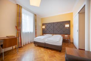 Schlafzimmer mit einem Bett, einem Schreibtisch und einem Tisch in der Unterkunft Villa Ceconi by Das Grüne Hotel zur Post - 100% BIO in Salzburg