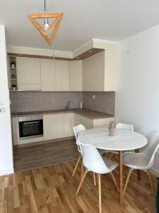 a kitchen with a white table and white chairs at Flora apartment in Lukavica