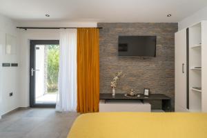 1 dormitorio con cama amarilla y TV en una pared de ladrillo en Studio Apartment Carpe Diem, en Drinovci