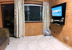 a room with a window with a fan and a television at Apartamento em GV in Governador Valadares