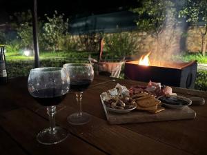 drewniany stół z dwoma kieliszkami wina i jedzeniem w obiekcie Cosy Mountain Villa in Nizepole w mieście Bitola