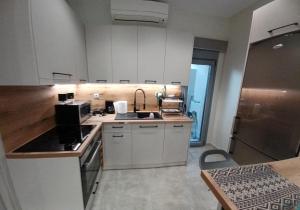 uma cozinha com armários brancos e um lavatório em Doukas Home em Mitilene