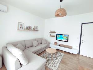 a white living room with a couch and a table at Saeri's Stylish Apartment in Shëngjin