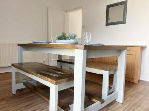 a dining table with a bench and a table with glasses on it at Wrightson House by Blue Skies Stays in Stockton-on-Tees