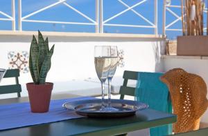a glass of wine sitting on a table with a plate at NEREA - Apulian Suite and Rooms in Monopoli