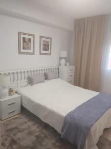 - une chambre blanche avec un grand lit et une fenêtre dans l'établissement Cerca del Mar, à Dénia