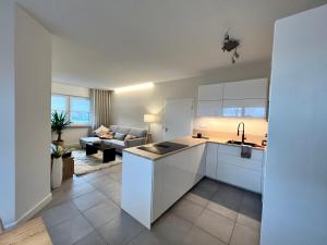 a kitchen with white cabinets and a living room at NEU 2023 Gemütliches Apartment im Eichsfeld in Leinefelde