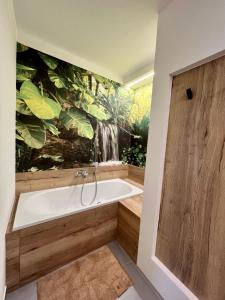 een badkamer met een bad en een watervalmuurschildering bij NEU 2023: Ferienwohnung THEO in Leinefelde