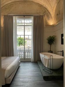 een slaapkamer met een bad, een bed en een raam bij Artemisia Domus - Giardino in Napels