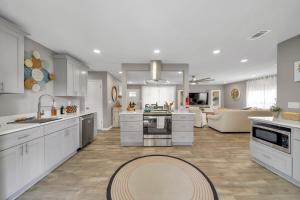 a large kitchen with white cabinets and a living room at Magnolia - Family-Friendly Comforts, TVs, Grill & Just Steps to the Beach! in Fort Walton Beach