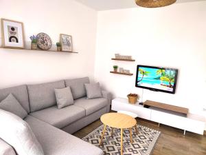 a living room with a couch and a tv at Saeri's Stylish Apartment in Shëngjin