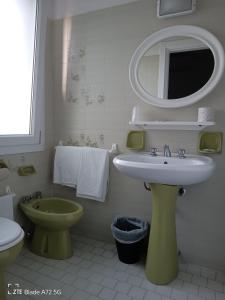 a bathroom with a sink and a toilet and a mirror at Ninfea rooms in Cervia