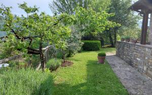 a garden with a tree and a stone wall at Casa Conny in Poppi