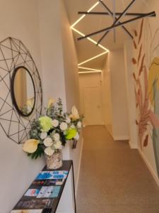 un corridoio con un vaso di fiori e uno specchio di Malaga a Tu Ritmo! Edificio muy tranquilo y moderno! a Málaga