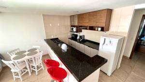 cocina con nevera blanca y mesa con sillas rojas en APARTAMENTO VISTA MAR Até 7 pessoas, en Arraial do Cabo 15 fotos más