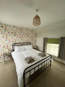 una camera da letto con un grande letto e carta da parati floreale di Peedie Cott Self-Catering, Orkney a St Margaret's Hope