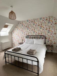 1 dormitorio con 1 cama grande y papel pintado con motivos florales en Peedie Cott Self-Catering, Orkney, en St Margaret's Hope