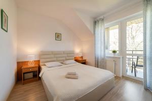 a white bedroom with a bed and a window at Mario Pokoje - Apartamenty in Jastarnia