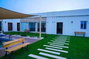 a patio with benches and grass and a building at Bahja Challet in As Suwayq