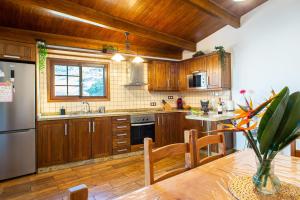 a kitchen with wooden cabinets and a table with a vase at Las Cuevitas del Gamonal in Santa Brígida