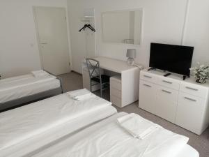 a room with two beds and a desk with a television at City-Pension-Bautzen in Bautzen