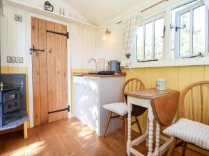 a small kitchen with a table and a stove at Shepherds Hut at The Hollies in Woodbridge