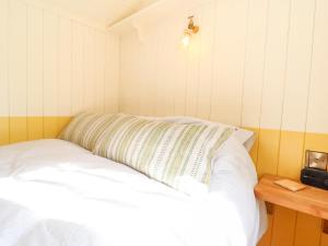 a bed in a small room with a pillow on it at Shepherds Hut at The Hollies in Woodbridge