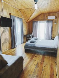 two beds in a room with wooden floors and windows at Keriya Hotel Shekvetili Kaprovani in Shekhvetili
