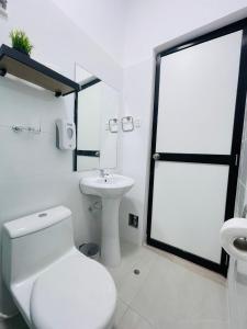 a white bathroom with a toilet and a sink at Casa La Merced in Tarapoto