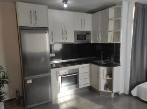 a kitchen with white cabinets and a stainless steel refrigerator at Apartamento CANDELA in Fuengirola