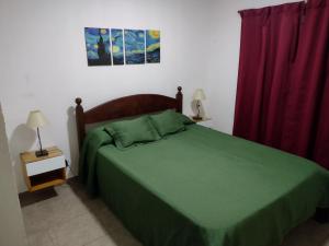 1 dormitorio con cama verde y cortina roja en Departamento en Loma Hermosa cercano a Palomar en Loma Hermosa