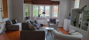 a living room with chairs and a table and windows at Innes Road Durban Accommodation Private Double Room with Private Bathroom in Durban