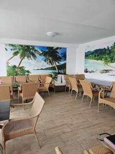 a restaurant with chairs and tables and a mural of the beach at Vila Angelys in Tuzla