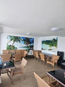 a room with chairs and tables and a mural of a beach at Vila Angelys in Tuzla