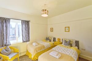 a bedroom with two beds and a chair and a window at The Shoreline Retreat in Lytham St Annes