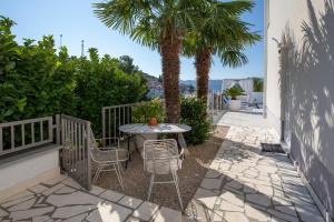 een patio met een tafel en stoelen en een palmboom bij Villa Mare in Klek