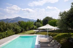 a swimming pool with an umbrella and chairs and a table and an umbrella at Sithonian Villa in Neos Marmaras