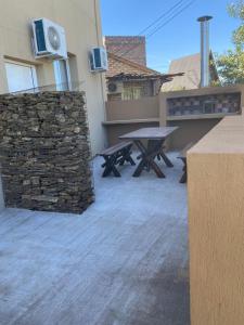 un patio con mesa de picnic y pared de piedra en Departamento sierra de la ventana en Sierra de la Ventana