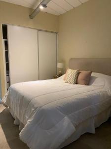 Un dormitorio con una gran cama blanca con almohadas. en Departamento sierra de la ventana en Sierra de la Ventana