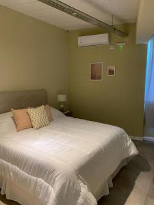 1 dormitorio con 1 cama grande y edredón blanco en Departamento sierra de la ventana en Sierra de la Ventana