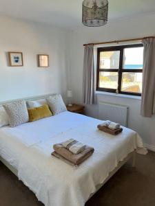 Un dormitorio con una cama blanca con toallas. en Rockview Beadnell - Perfect Family Retreat, en Beadnell
